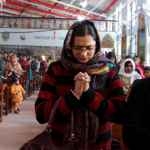 Un hombre pinta sobre un cartel que dice “Jesús no es Dios”, y lo transforma  en “Jesús es Dios”.